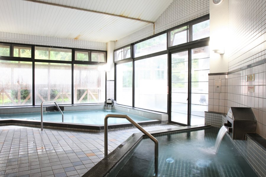窓から緑の木漏れ日が溢れる、広々とした大浴場は心も体も芯まで温まる心地良さ。