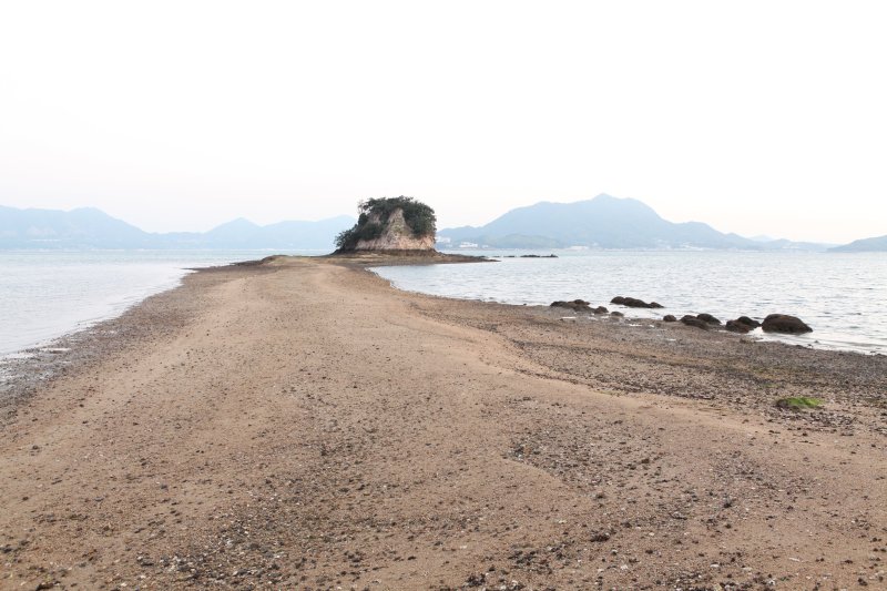 車が横に約2台ほど置ける程度の幅の砂浜の道が現れ、陸と沖に浮かぶ大角豆島への架け橋となる。