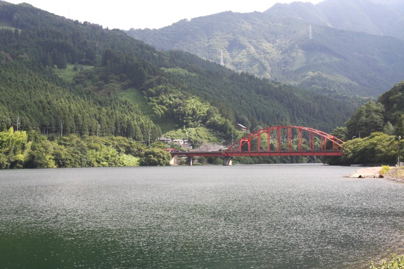 人造湖にかかる赤いトラス橋。まわりの緑が湖面に写りコントラストが美しい。