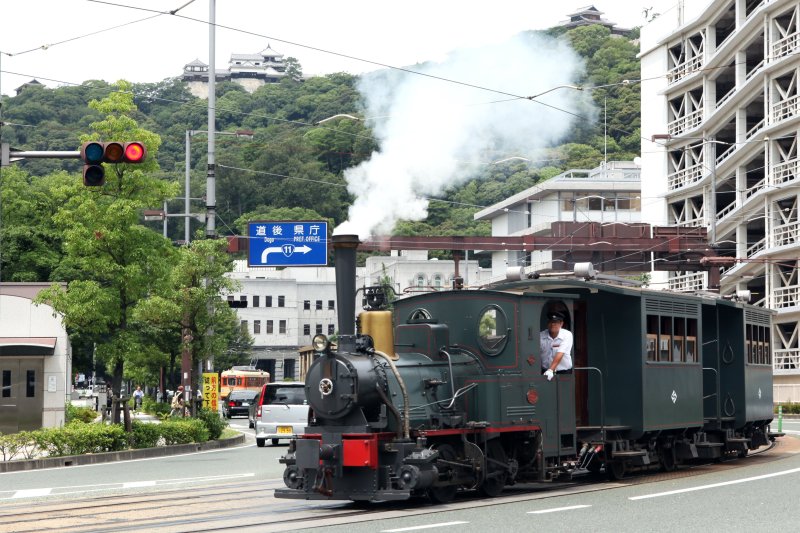 松山城を横目に、蒸気を吐きだしながら市内を走る「坊っちゃん列車」。