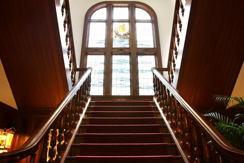 細部にまで意匠の施された階段。大型のステンドグラスと深紅のカーペットとの組み合わせは、シネマのワンシーンを想起させられる。