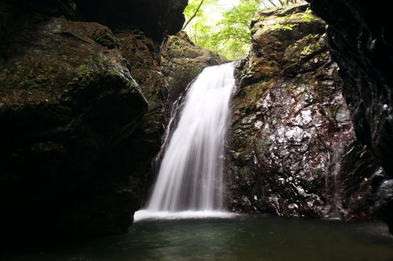 自然の力強さを感じる巨大な岩壁に囲まれ、その隙間を流れ落ちる岩戸の滝。