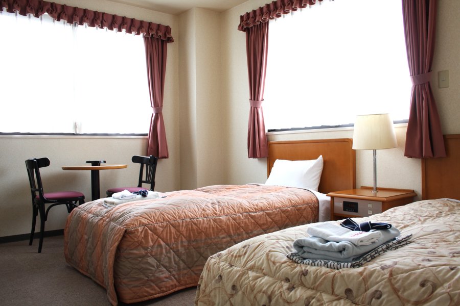 ゆったりとくつろげる洋室の宿泊部屋にはベッドとリビングが完備され、窓からは西条市内の田園風景や四国山脈を望むことができる。