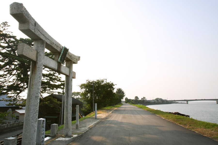 勇壮な加茂川の土手に佇む嘉母神社の鳥居。