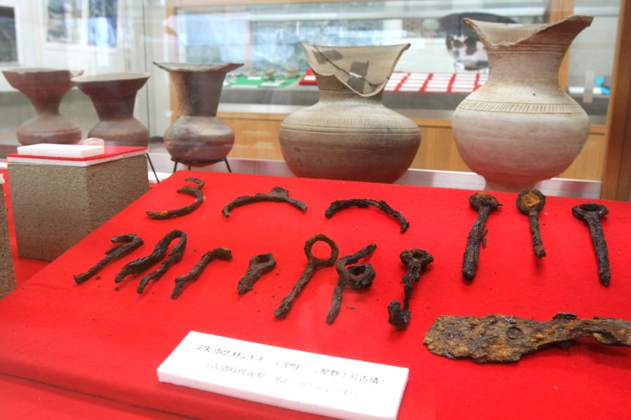 縄文土器や石器のほかに、鉄製の馬具や古銭など貴重な金属資料が丁寧に並べられ展示されている。