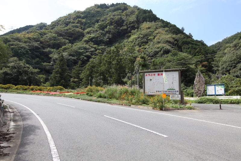 長浜地区から出石寺へ向かう県道を走っていくと右手に大わらじと看板があり、正面に目をやると山の中腹辺りに左を向いた顔面のような人面岩が見える。