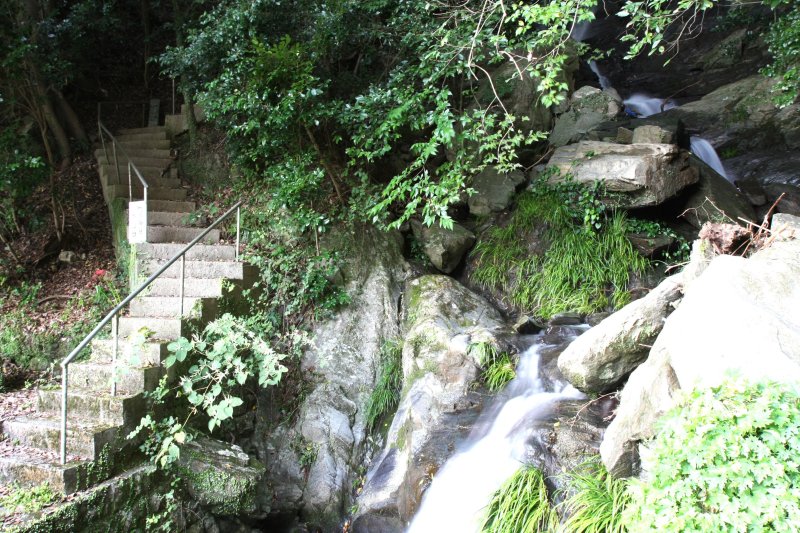 本殿の脇から流れ落ちる、落差約20mの滝を横目に参道が上へと続いている。