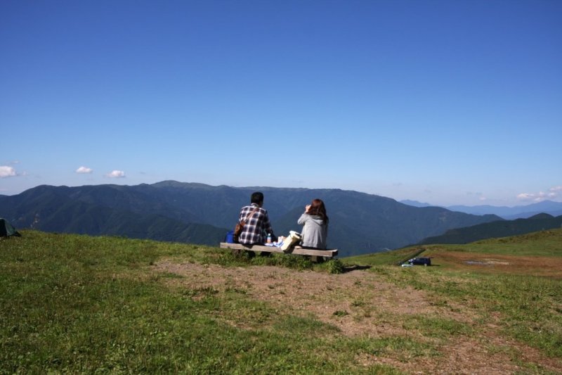 目の前に山々の稜線がパノラマで広がる広場では、休憩ができる東屋やベンチも設置されている。