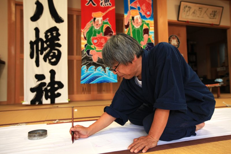 図柄や文字は下絵などはなく、直接手描きで金巾（かねきん）という木綿の布に描いていく。