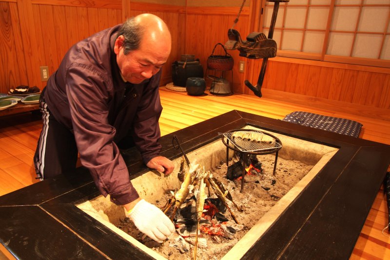 オーナーの手によって囲炉裏でじっくりと焼かれる鮎の塩焼き。