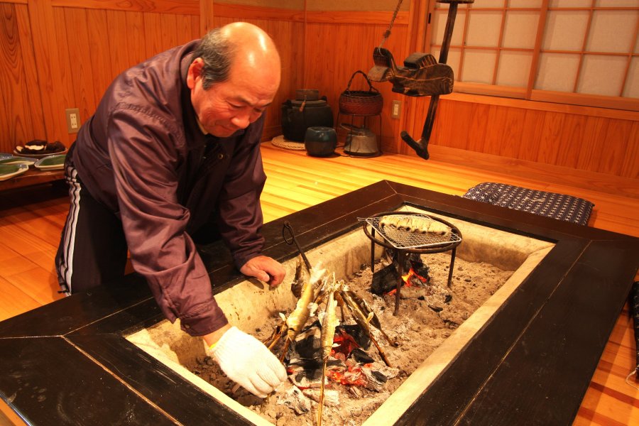 オーナーの手によって囲炉裏でじっくりと焼かれる鮎の塩焼き。