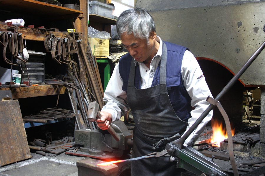 1本の鋼材を1500度の熱で炙りながら、ハンマーで叩いて伸ばし形を作っていく。職人技が光る工房は、見学することもできる。