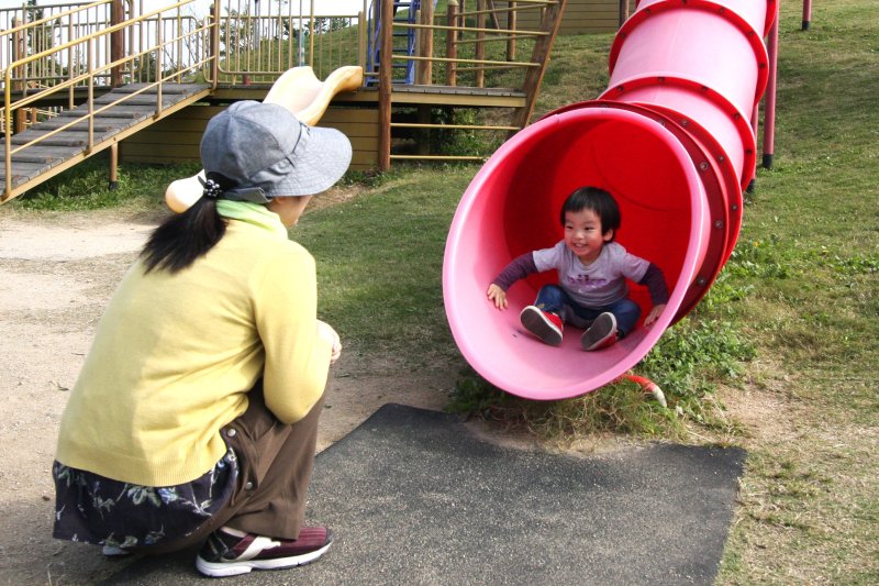 晴天が広がる大空のもと、大きなすべり台で元気一杯遊ぶ子供の表情は笑顔いっぱい。